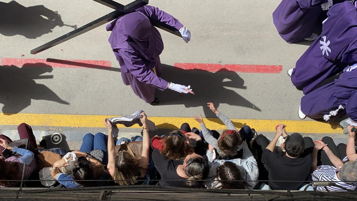 Un nazareno entrega un caramelo a una niña en la procesión del Viernes Santo por la mañana en Murcia.