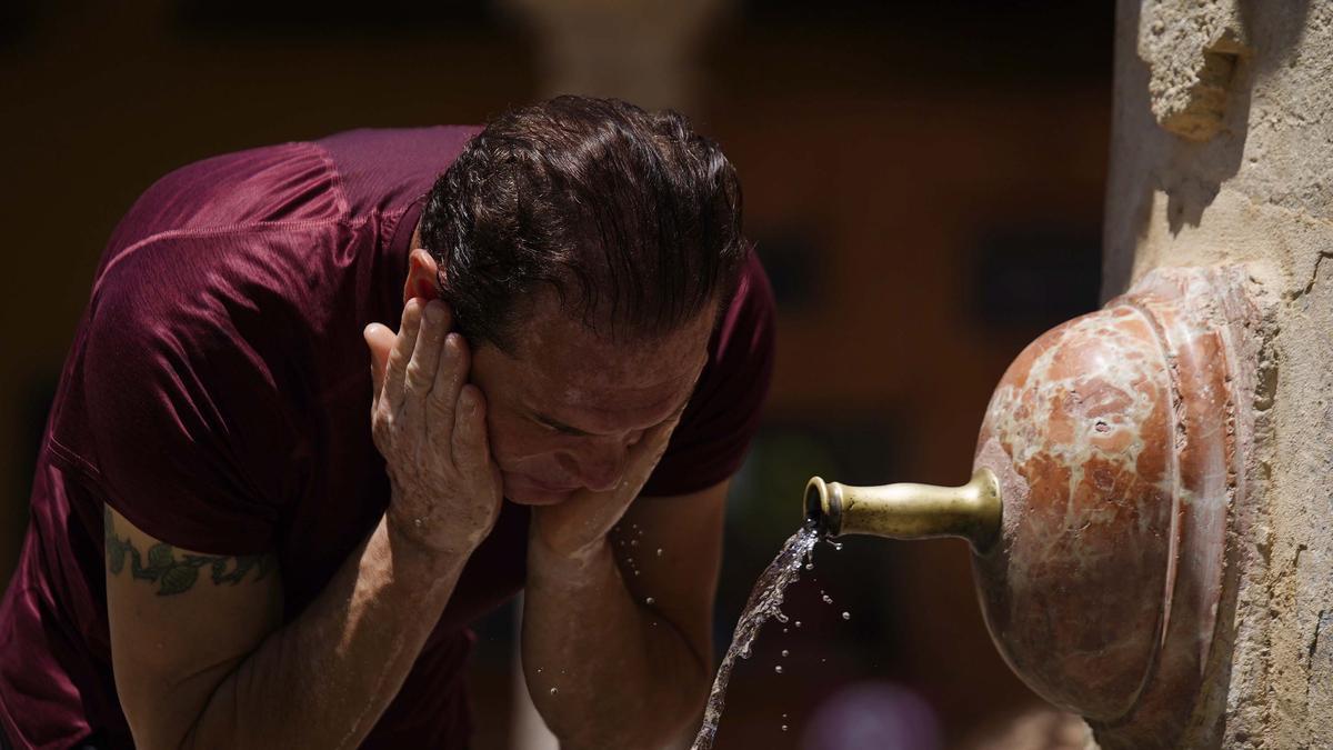 Un hombre se refresca en una fuente.