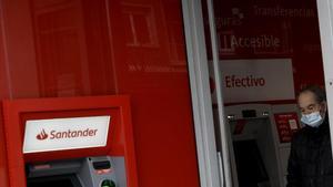 Un hombre con mascarilla saca dinero de un cajero del Banco Santander en Madrid, el pasado 21 de abril.