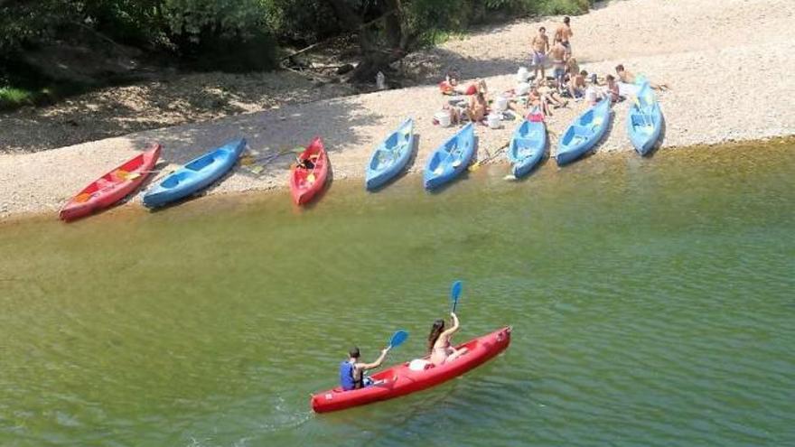 Una pareja, ayer, avanzando por el Sella en Llordón mientras un grupo de jóvenes descansa en un pedrero.