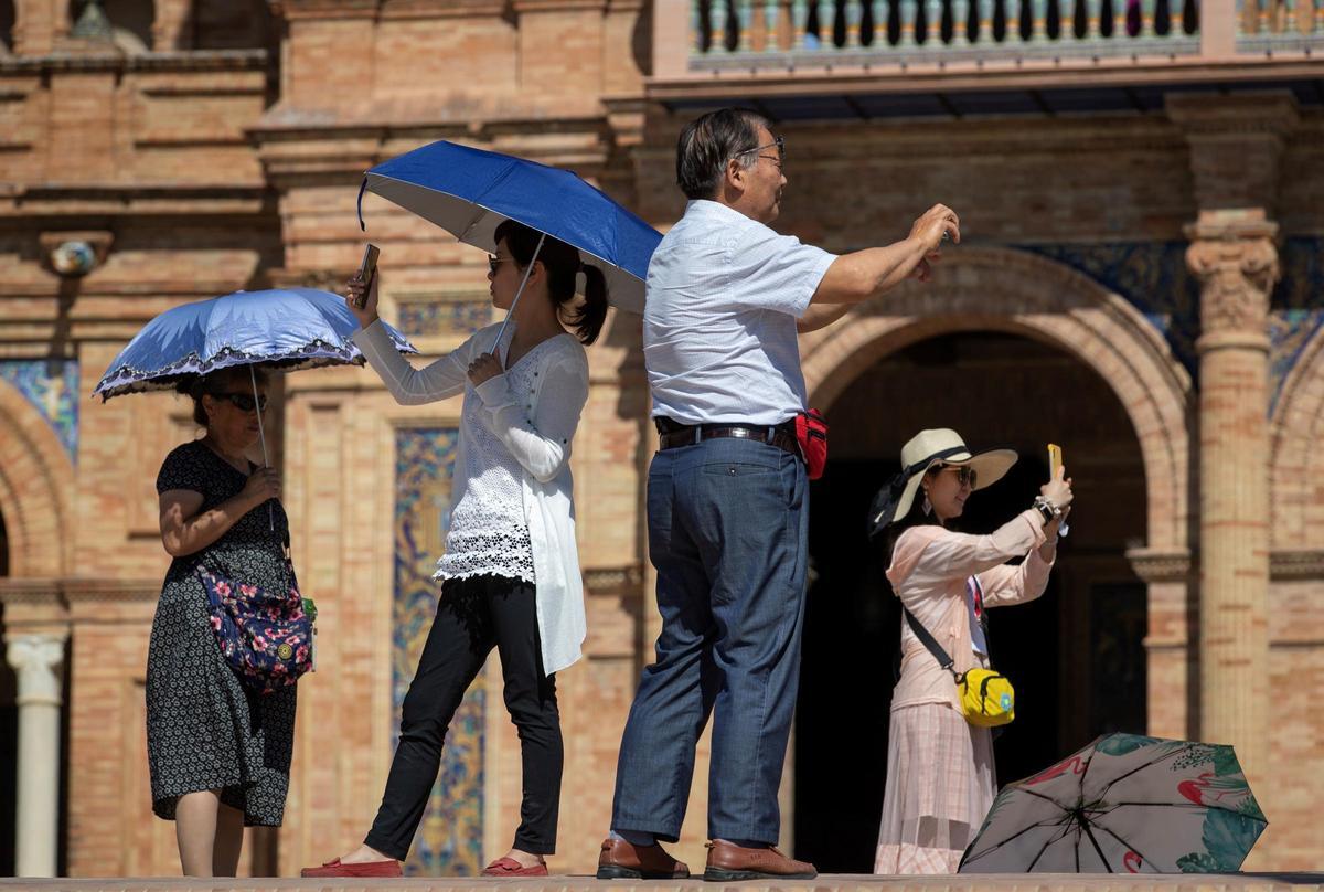 Varios turistas asiáticos se fotografían en la Plaza de España de Sevilla.