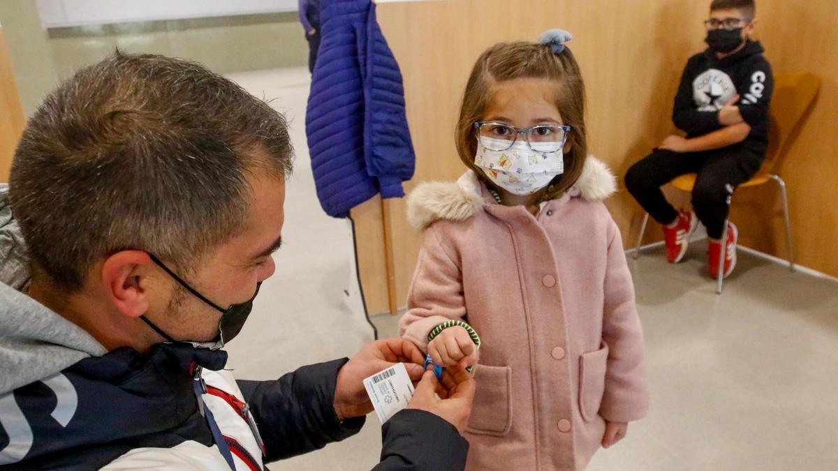 Un padre coloca a su hija la pulsera que regala el Sergas