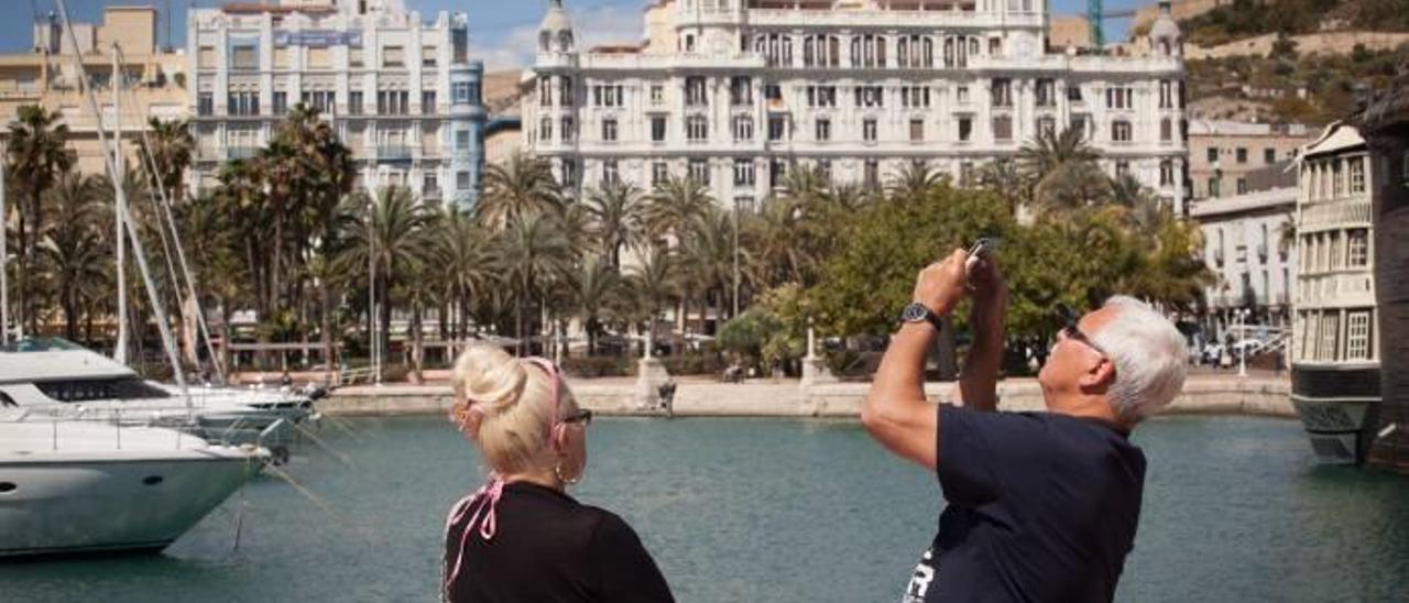 Una pareja de cruceristas toma fotos de Alicante frente a la Explanada tras descender del último barco que amarró en el puerto.