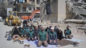 Un grupo de voluntarios basijis -milicia islámica- reza este miércoles, al lado de un edificio destruido en los bombardeos israelíes-estadounidenses contra Irán en la calle en la calle Kargar, cerca de la plaza Engelab en Teherán