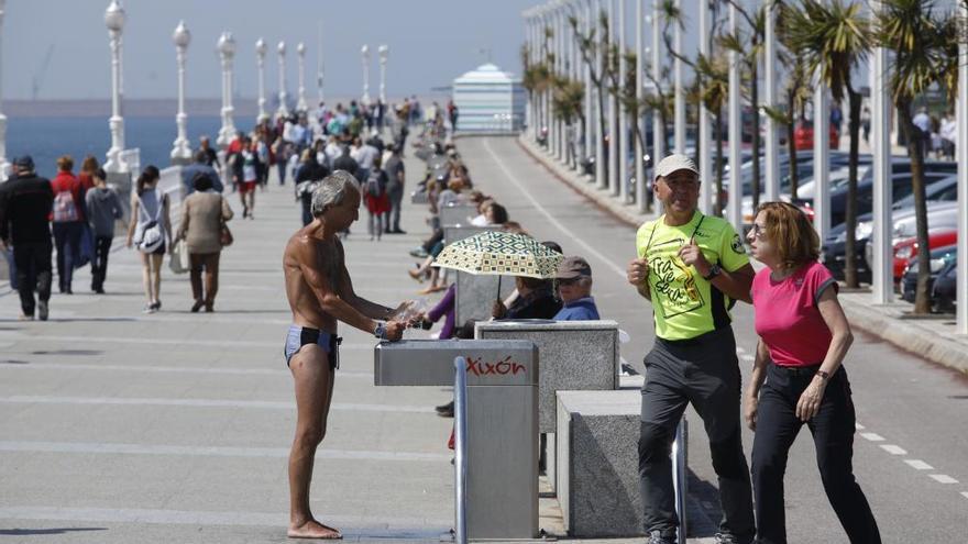 Un bañista se refresca en Gijón.