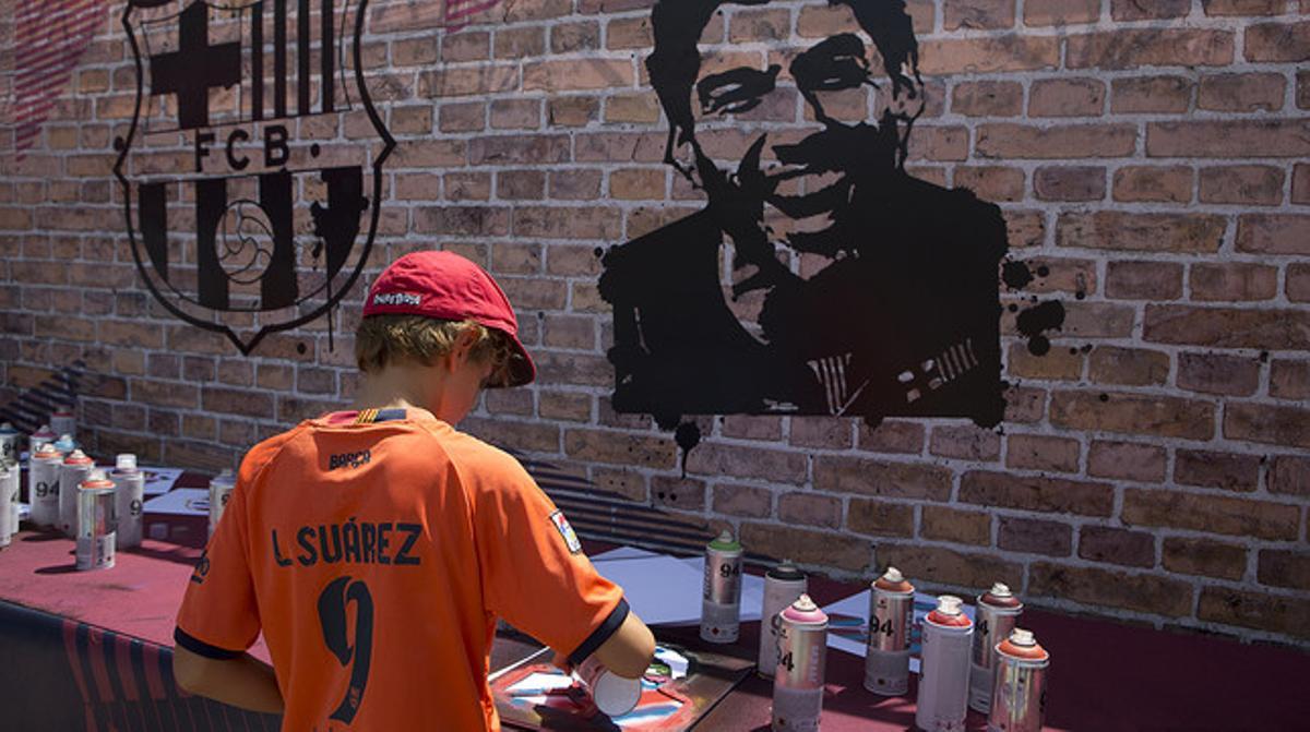 Un niño dibuja a sus ídolos con espray, en uno de los talleres organizados en el Camp Nou.