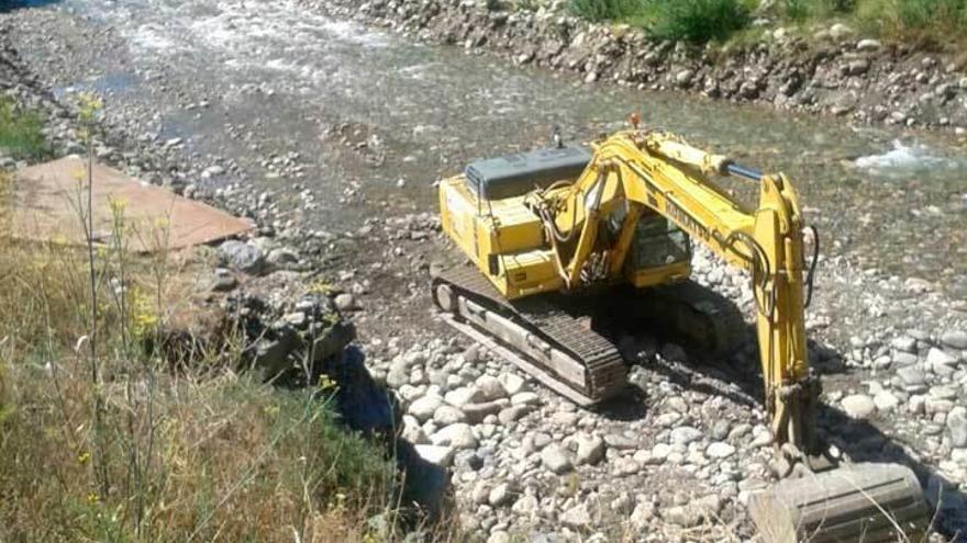 Una máquina ejecuta las labores a la orilla del río a su paso por Collanzo.