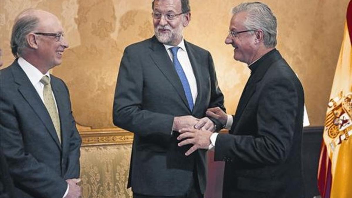 El obispo Joan-Enric Vives, copríncipe de Andorra, saluda a Rajoy y Montoro, ayer en La Seu d'Urgell.