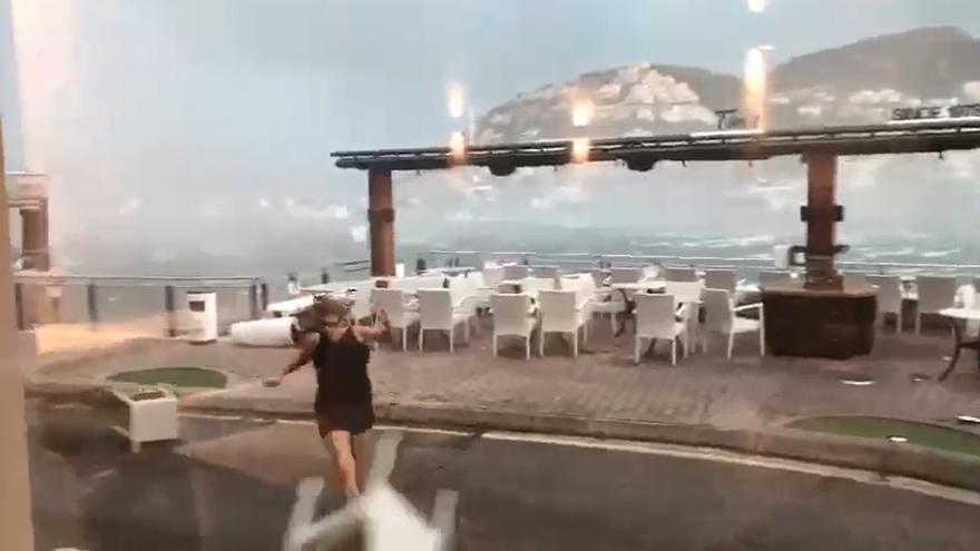 Eine Frau flüchtet am Sonntag (27.8.) vor den bei einem heftigen Unwetter herumfliegenden Stühlen in Port d'Andratx.