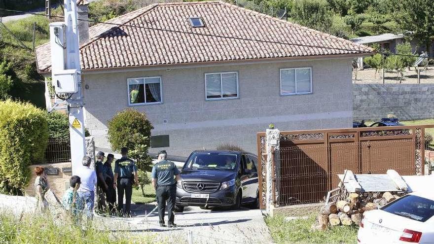 El furgón fúnebre abandona la vivienda de Filgueiras; a la derecha, al fondo, el garaje donde se hallaron los cuerpos.