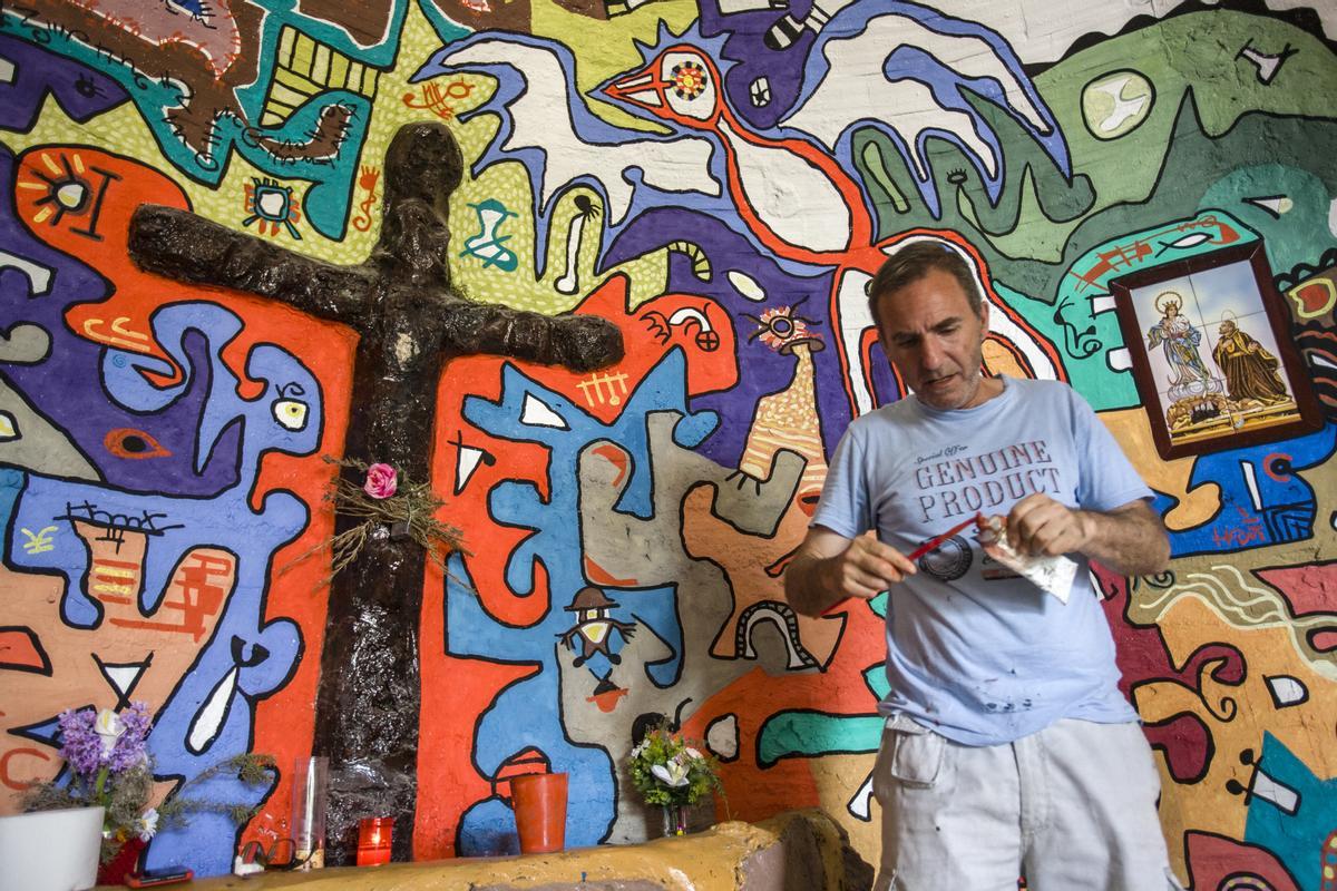 El autor ante una cruz pintada en el templo, junto a la que se han colocado flores y velas.