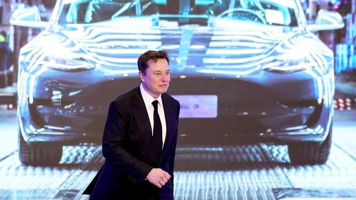 Elon Musk, junto a la imagen  de un coche Tesla.