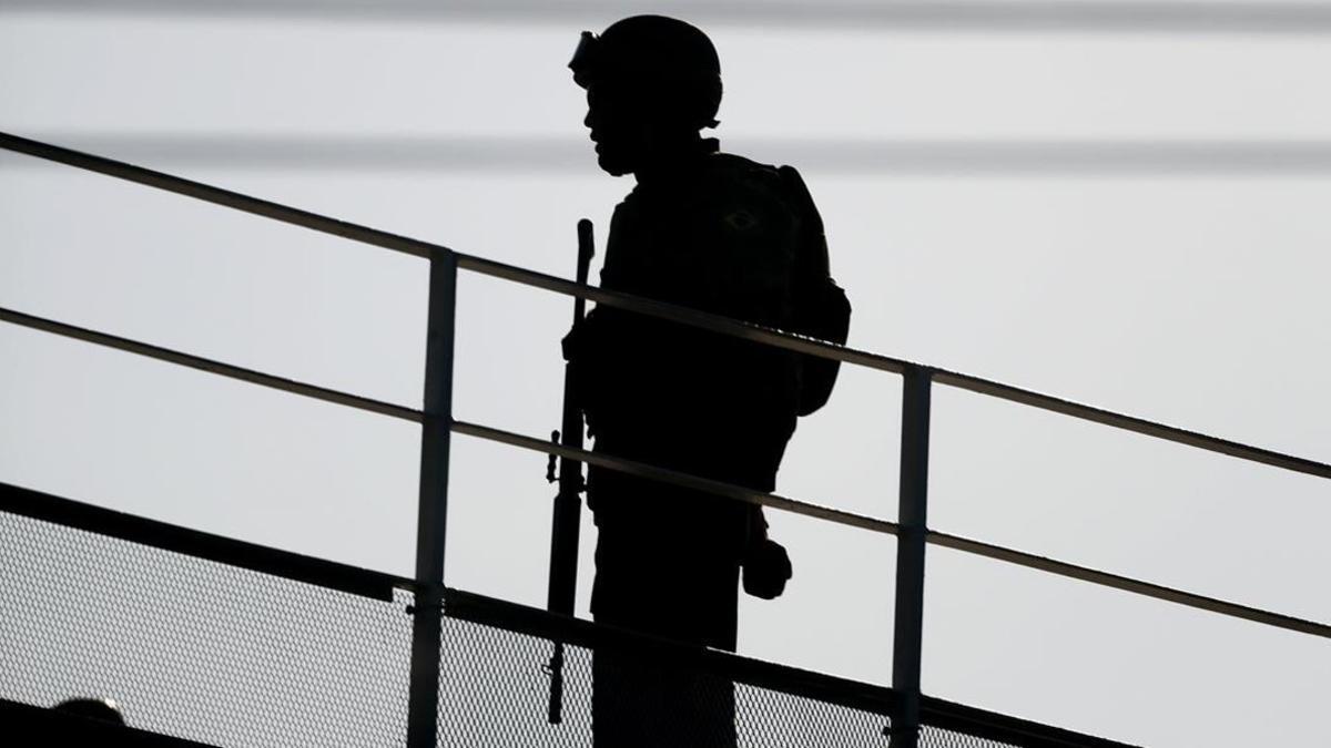 Un militar vigila desde un puente en una ciudad tomada por las fuerzas de seguridad.