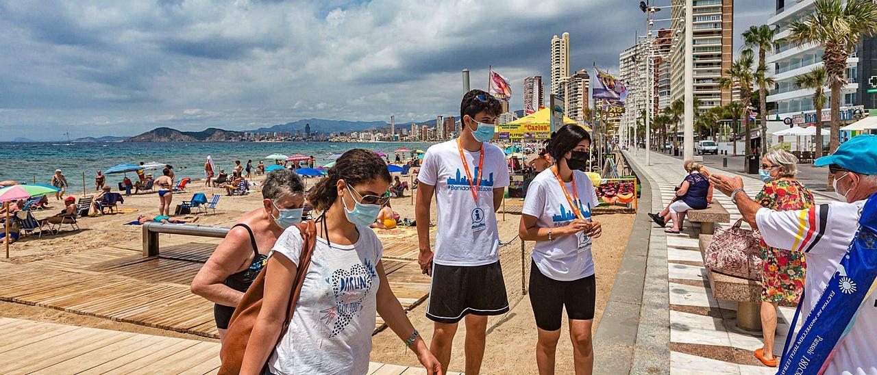 Dos de los 58 auxiliares que ya han empezado a trabajar en las playas de Benidorm informando a los usuarios de los arenales.  | DAVID REVENGA