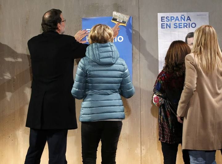 Spain's Prime Minister and People's Party (PP) candidate Mariano Rajoy puts up a poster during a rally at the start of the official campaign period for Spain's general election in Madrid