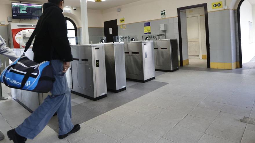 Una viajera pasa junto a los tornos de acceso al andén de la estación sierense. En frente, la puerta de los baños.