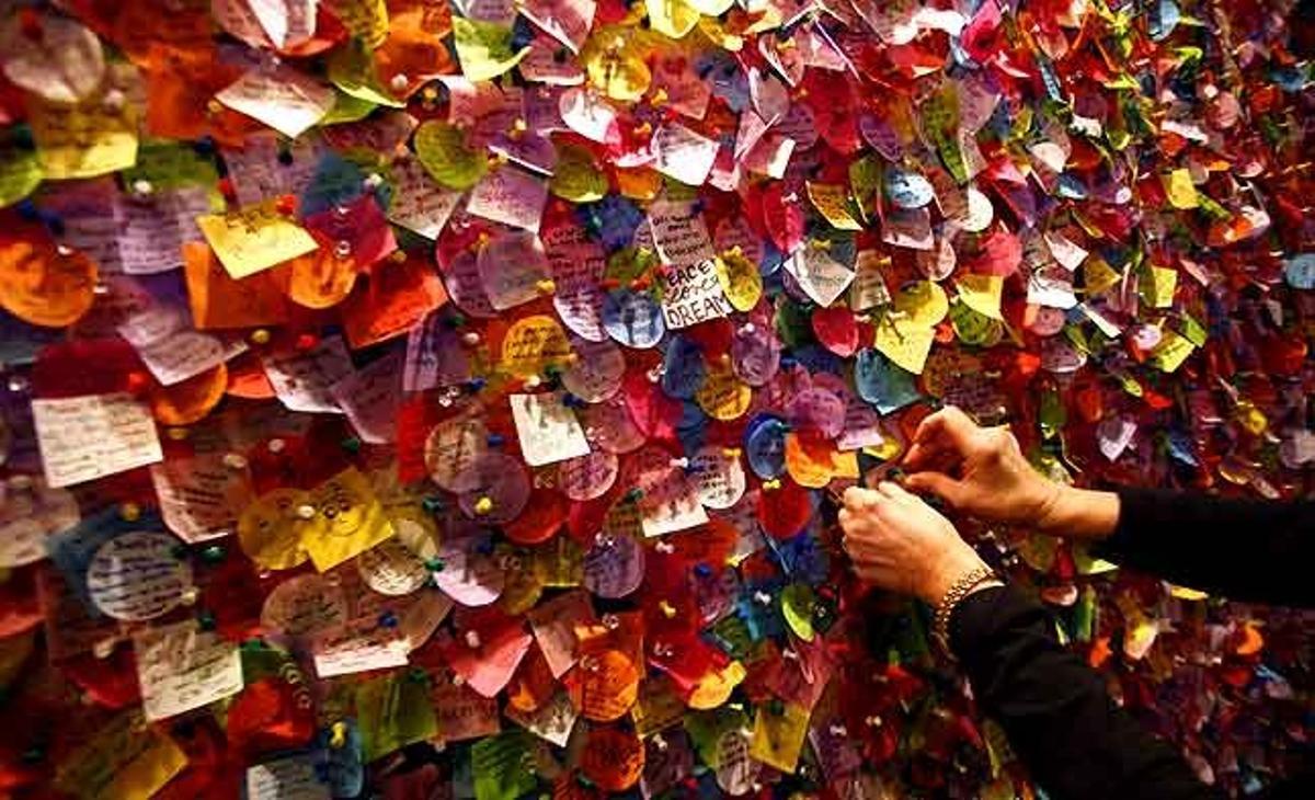 Una dona penja un desig per al nou any en un mural ple de papers al centre d’informació de Times Square a Nova York (Estats Units).