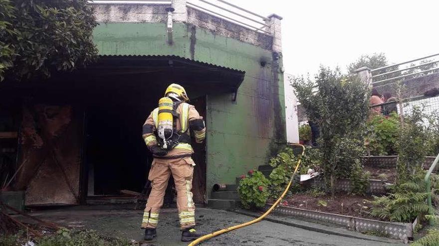 Un bombero durante las labores de extinción del incendio en el bajo de la vivienda. // G.N.