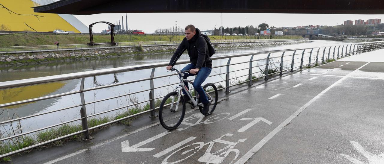 Un usuario del carril bici que bordea la ría de Avilés y que se conectará con la playa de San Juan.