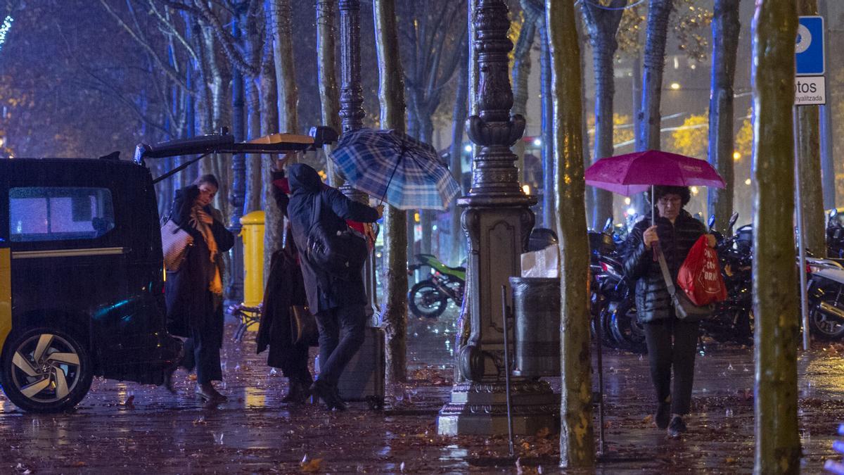 Lluvia de tarde que ha obligado a los paseantes a utilizar los paraguas en los alrededores de la Illa Diagonal