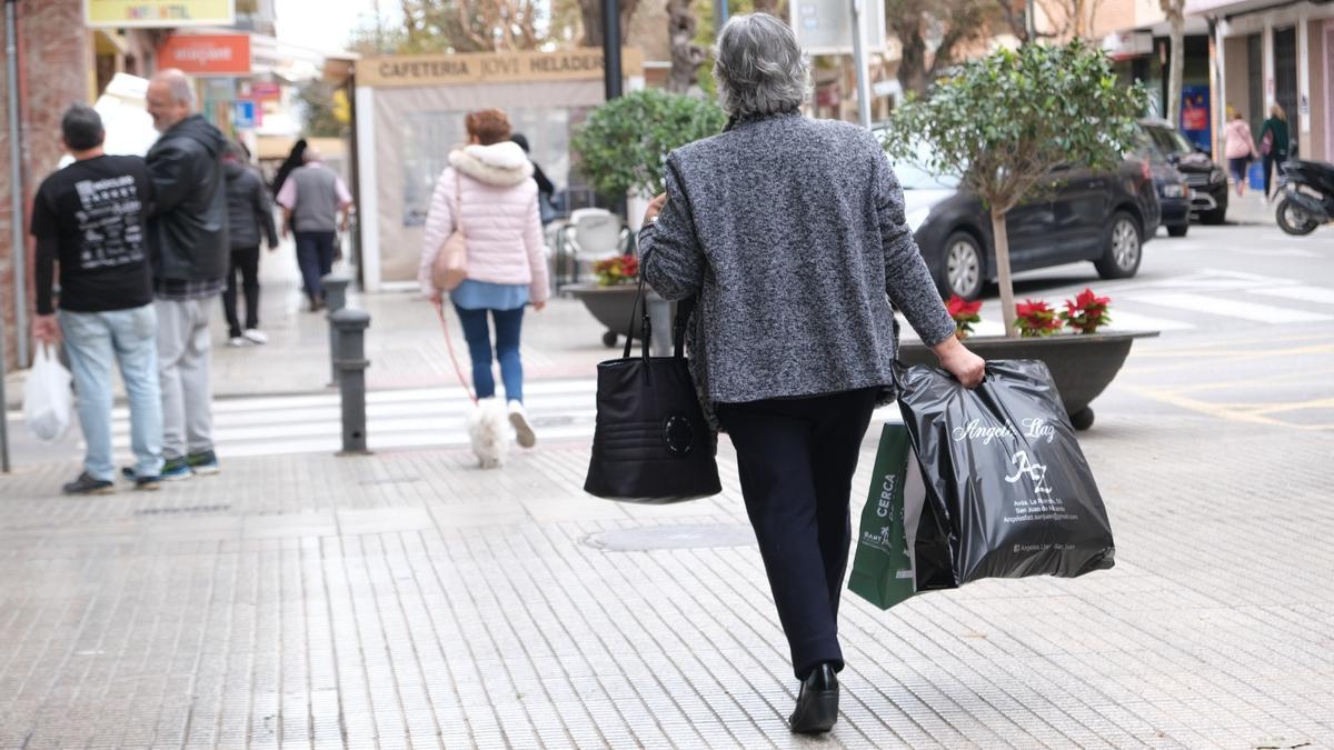 Una mujer camina por la Rambla con varias bolsas de la compra este invierno.