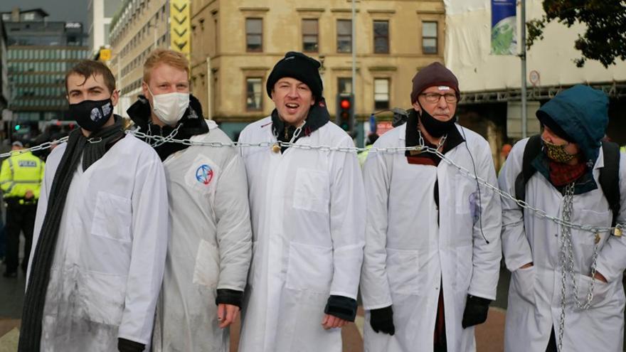 Miembros de Scientist Rebellion encadenados en el puente King George V de Glasgow, que originó en noviembre de 2021 el primer arresto masivo de científicos por la crisis climática.