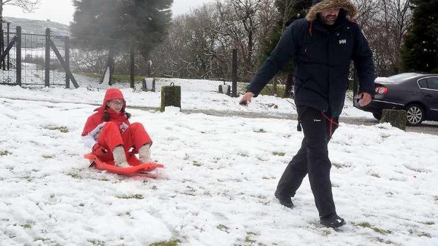 Un padre juega con su hija en la nieve en A Lama. // Rafa Vázquez