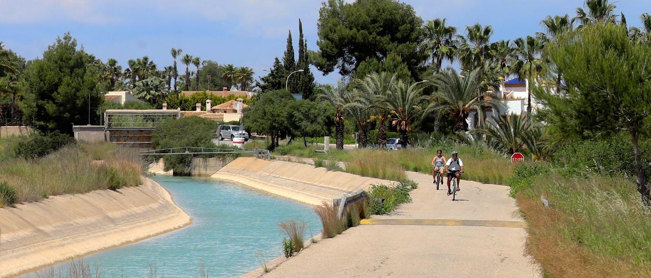 Dos cliclistas pedalean junto a uno de los canales que llega agua del Tajo al embalse de La Pedrera