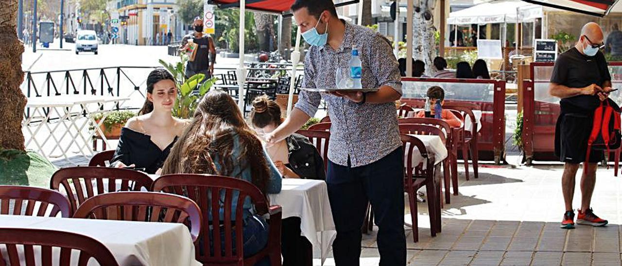 Un camareroatiende una terrazaen el puerto.