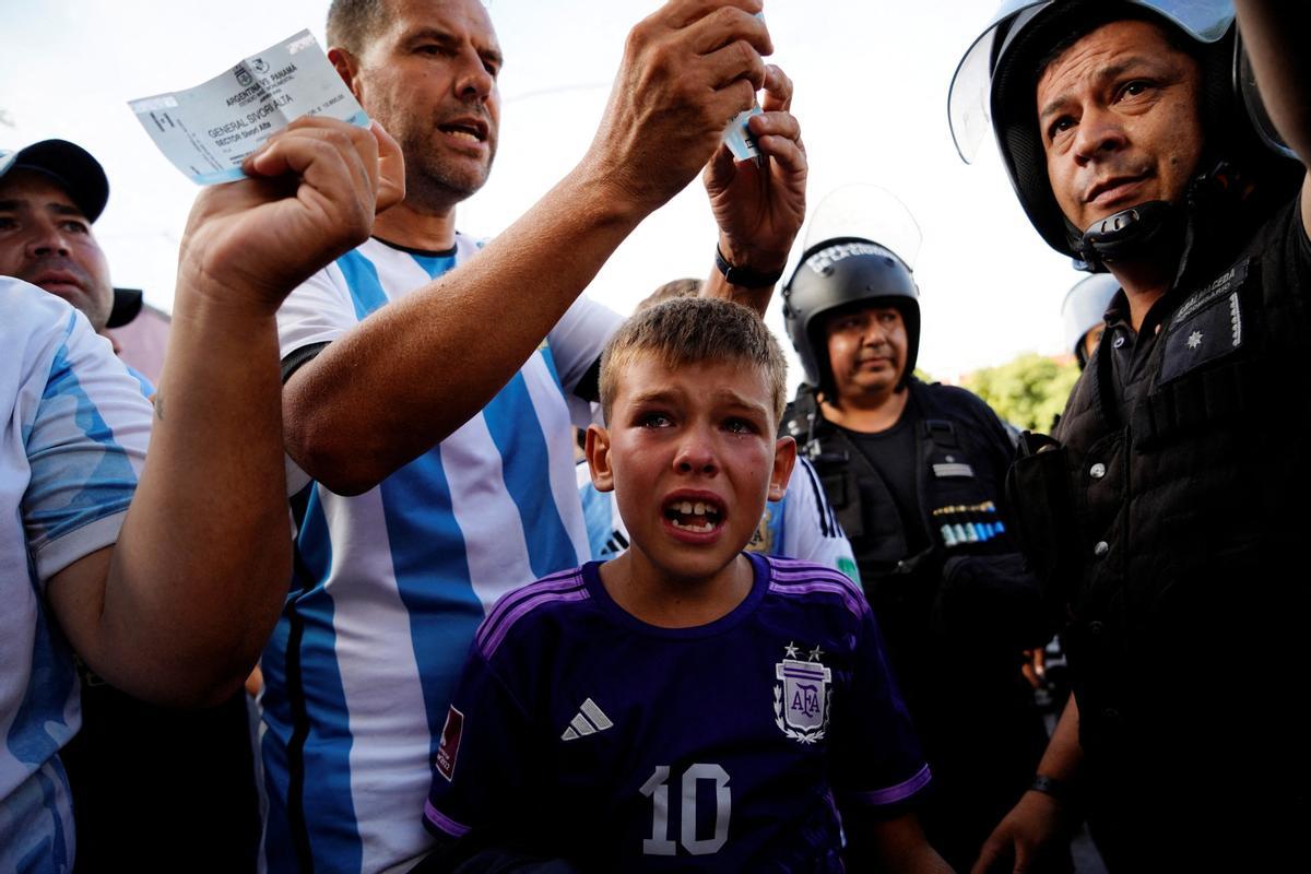 Los aficionados argentinos reaccionan después de que la seguridad rechace sus entradas fuera del estadio antes del partido 