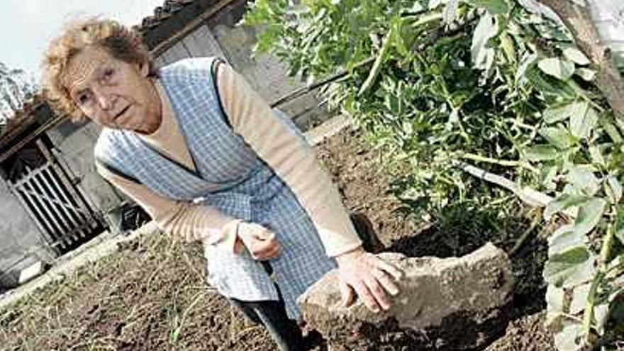 La propietaria de la casa muestra la piedra que cayó en el jardín. / j.l. oubiña