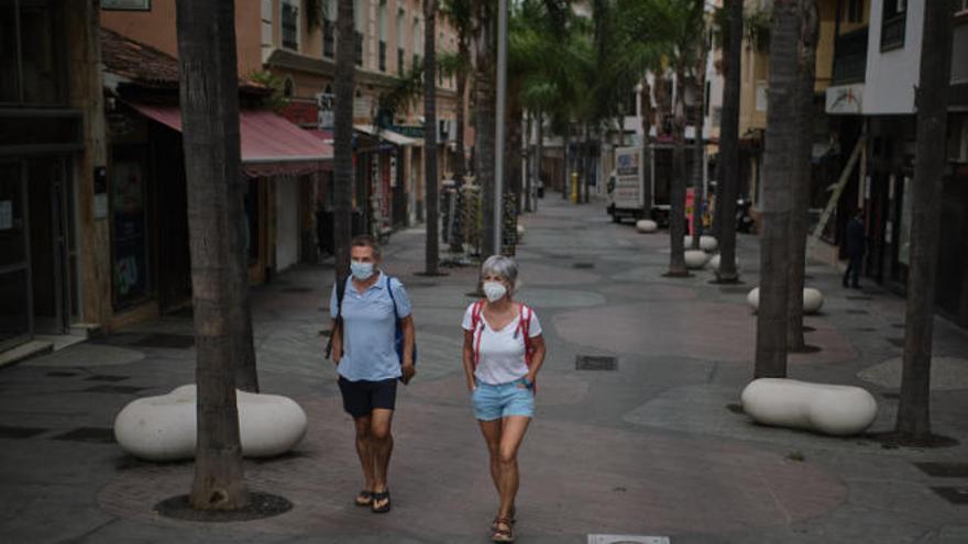 Una pareja pasea portando mascarillas por una desierta Calle de la Hoya en el Puerto de la Cruz, en Tenerife.