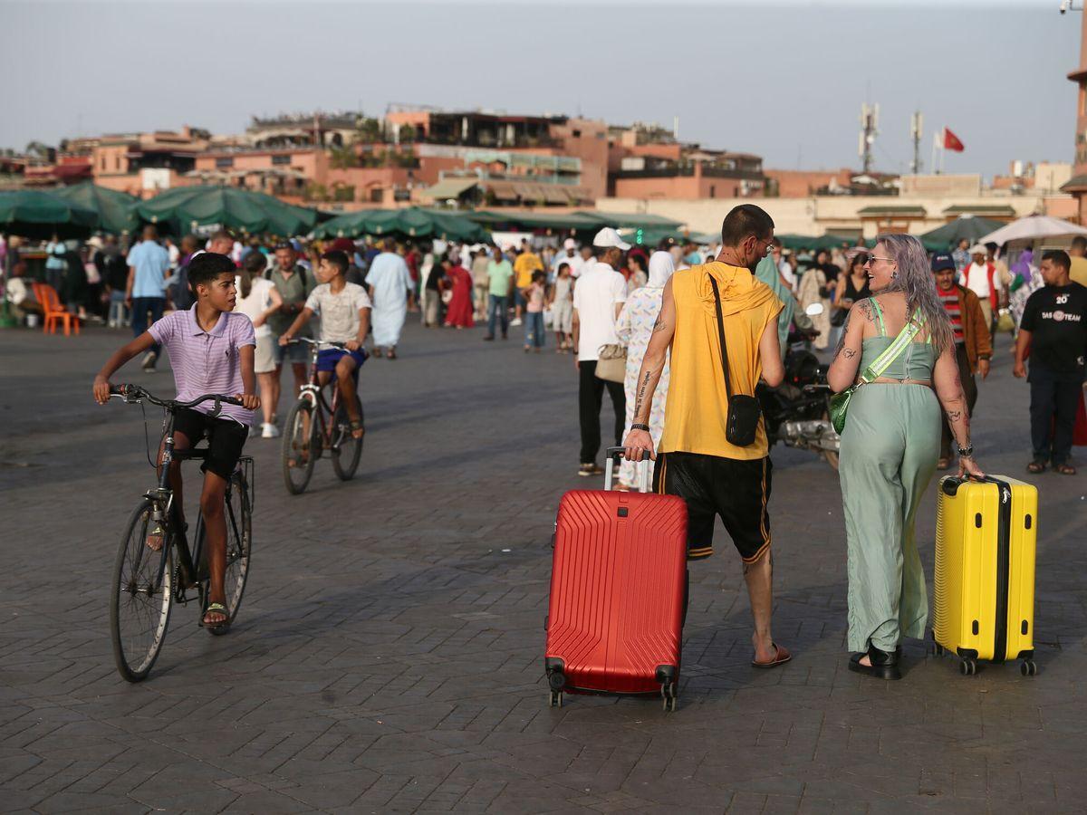 Una pareja de turistas arrastra sus maletas por la plaza de Yamaa el Fna de Marrakech, en Marruecos.