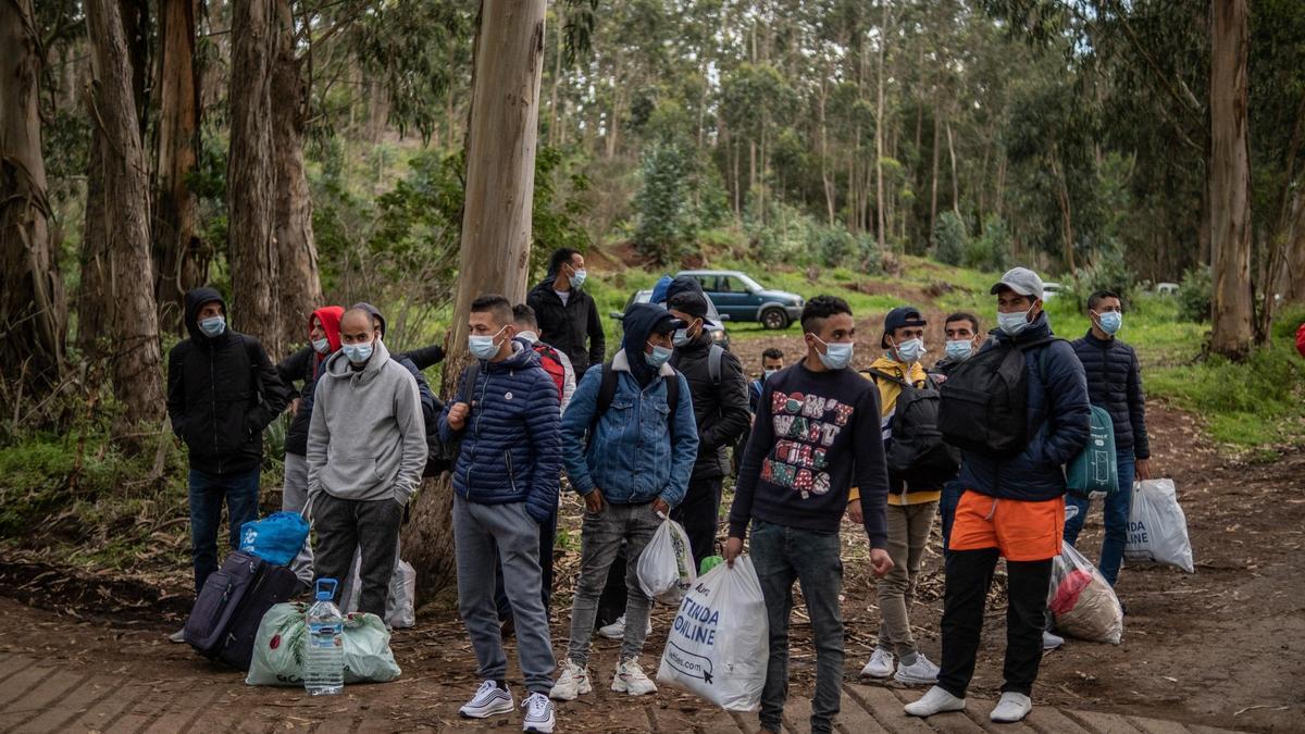 Migrantes en la entrada de acceso al campamento de Las Raíces