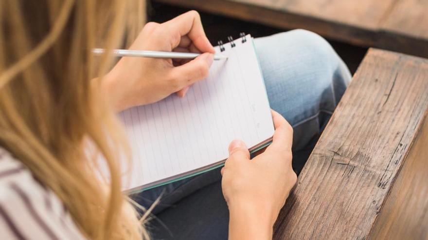 Joven escribe en un cuaderno