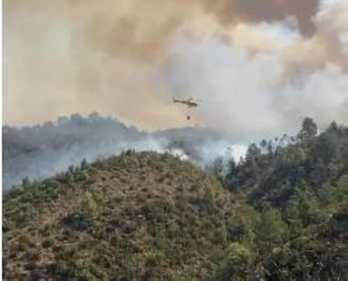 Un helicóptero transportando agua a uno de los focos del incendio de La Peña