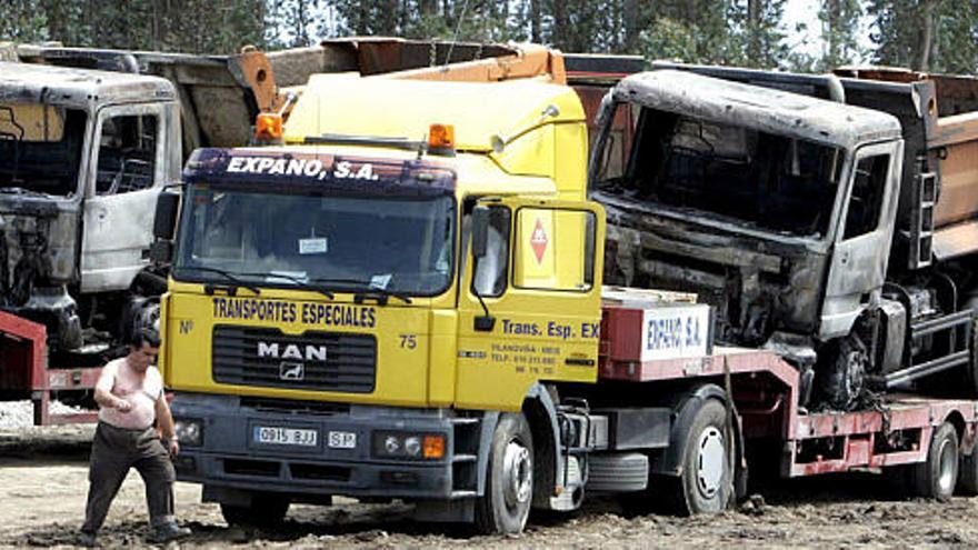 Los dos camiones completamente calcinados ayer en Rois son colocados en remolques de la empresa propietaria para su traslado.