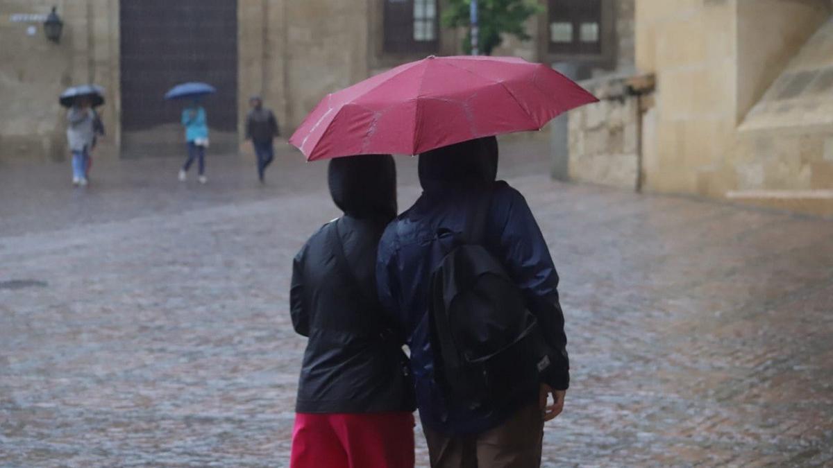 Una pareja se protege de la lluvia con un paraguas en el entorno de la Mezquita Catedral de Córdoba.