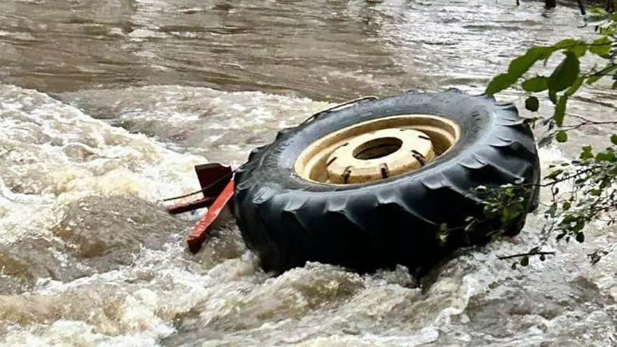 Un home s'agafa a la roda d'un tractor per evitar ser arrosegat per la corrent del riu Segre