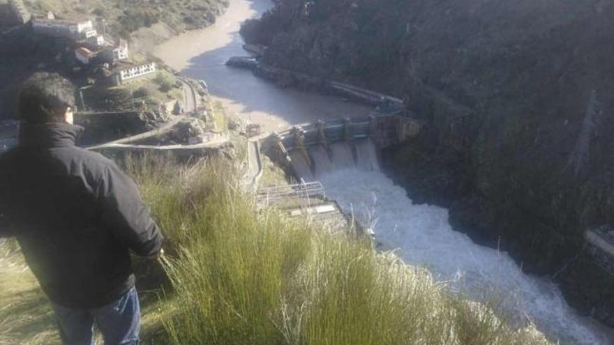 Una persona observa, desde la vertiente lusa, el desembalse de agua en la presa de Castro.