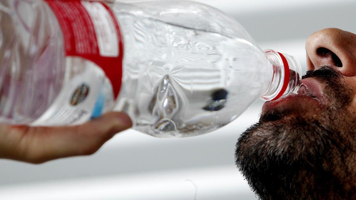 Una persona bebe agua para refrescarse.