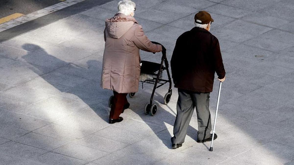 Una pareja de ancianos pasea por la calle.