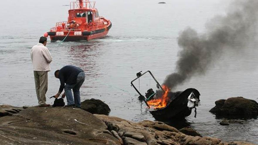 Investigadores comprueban los restos de la planeadora en llamas mientras Salvamento Marítimo la remolca.  // Carlos Pereira