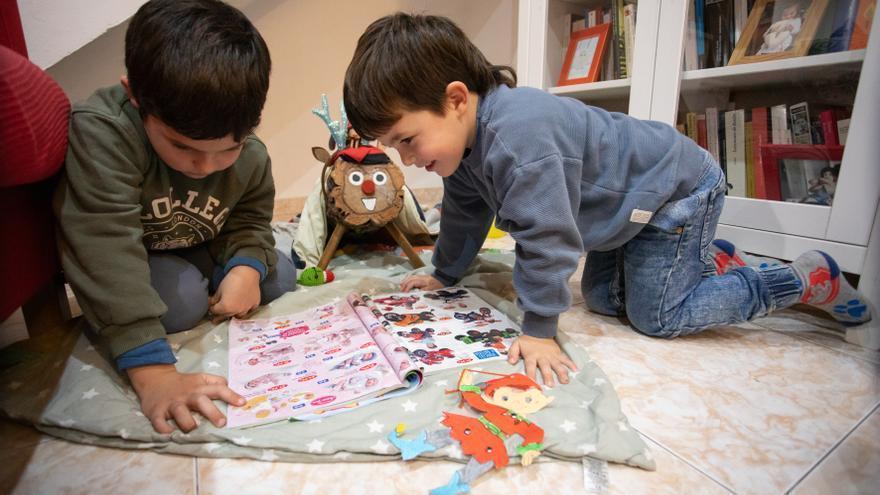 Motos para niños, muñecos bebés con fondo rosa &quot;para niñas&quot;: dos niños ojean catálogos de juguetes de Navidad, este mes de diciembre.
