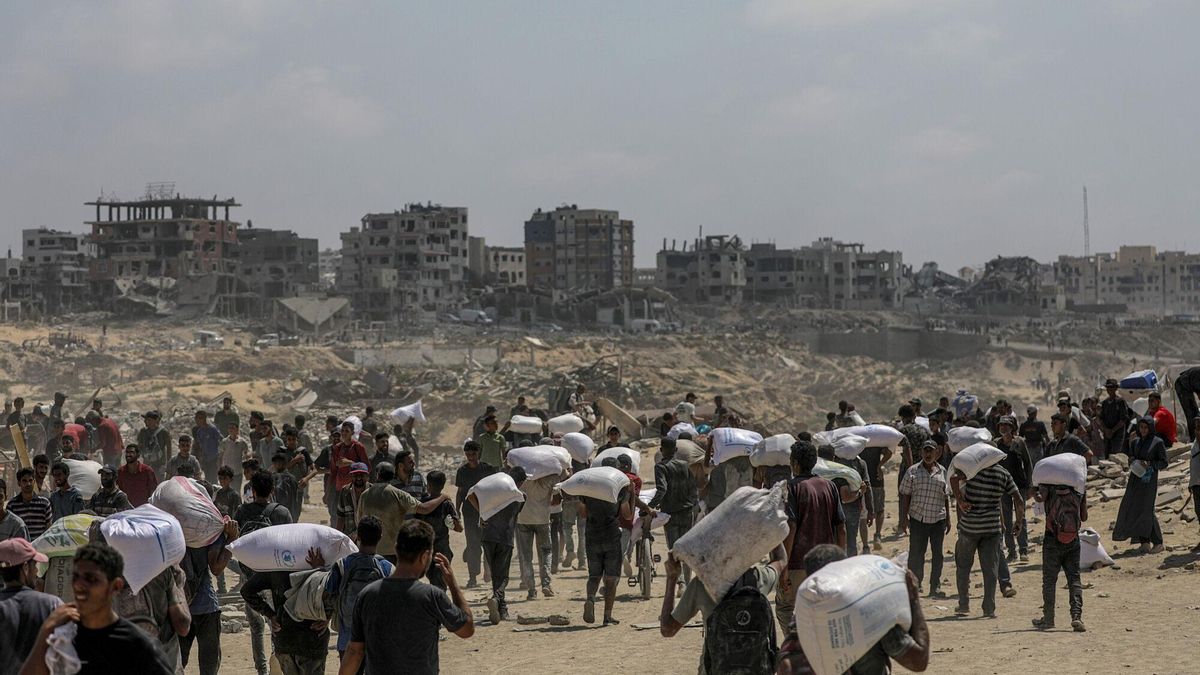 Palestinos desplazados transportan sacos de harina cerca de un punto de distribución de alimentos al norte de la Franja de Gaza.