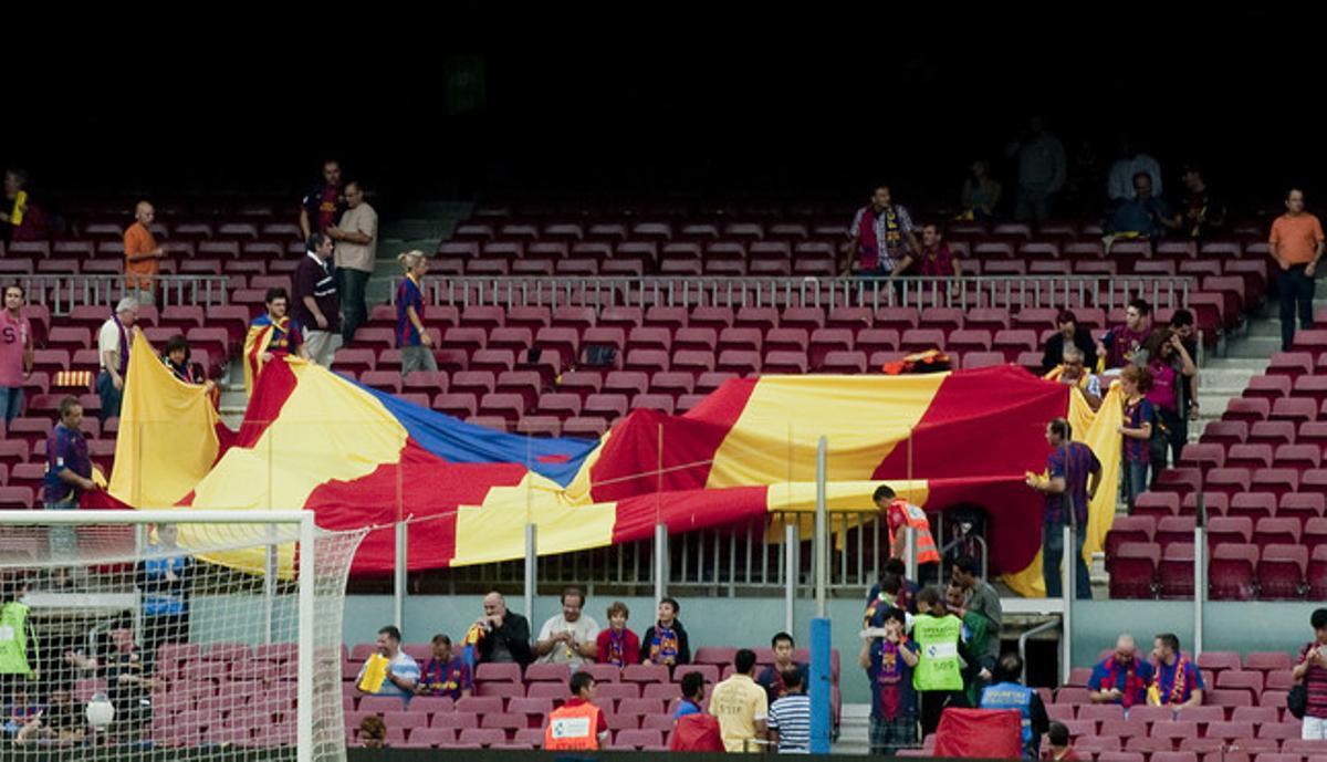 Aficionats preparen les seves banderes al gol nord del Camp Nou en les hores prèvies a l’inici del partit.