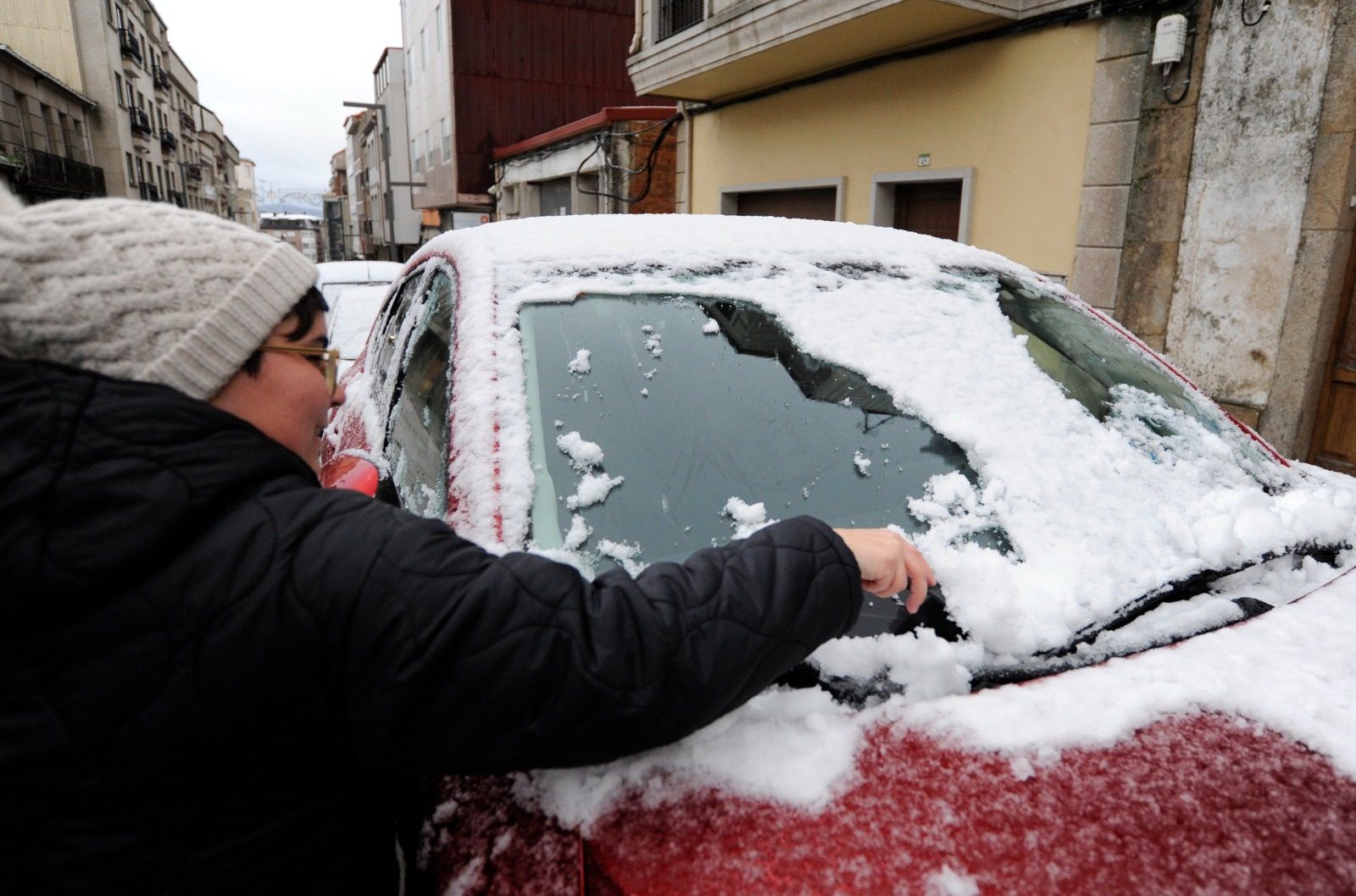 Vecina de Lalín retirando nieve del parabrisas