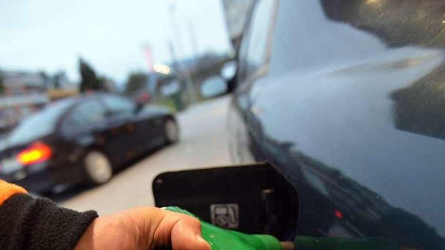 Un operario de una gasolinera reposta combustible en un coche.