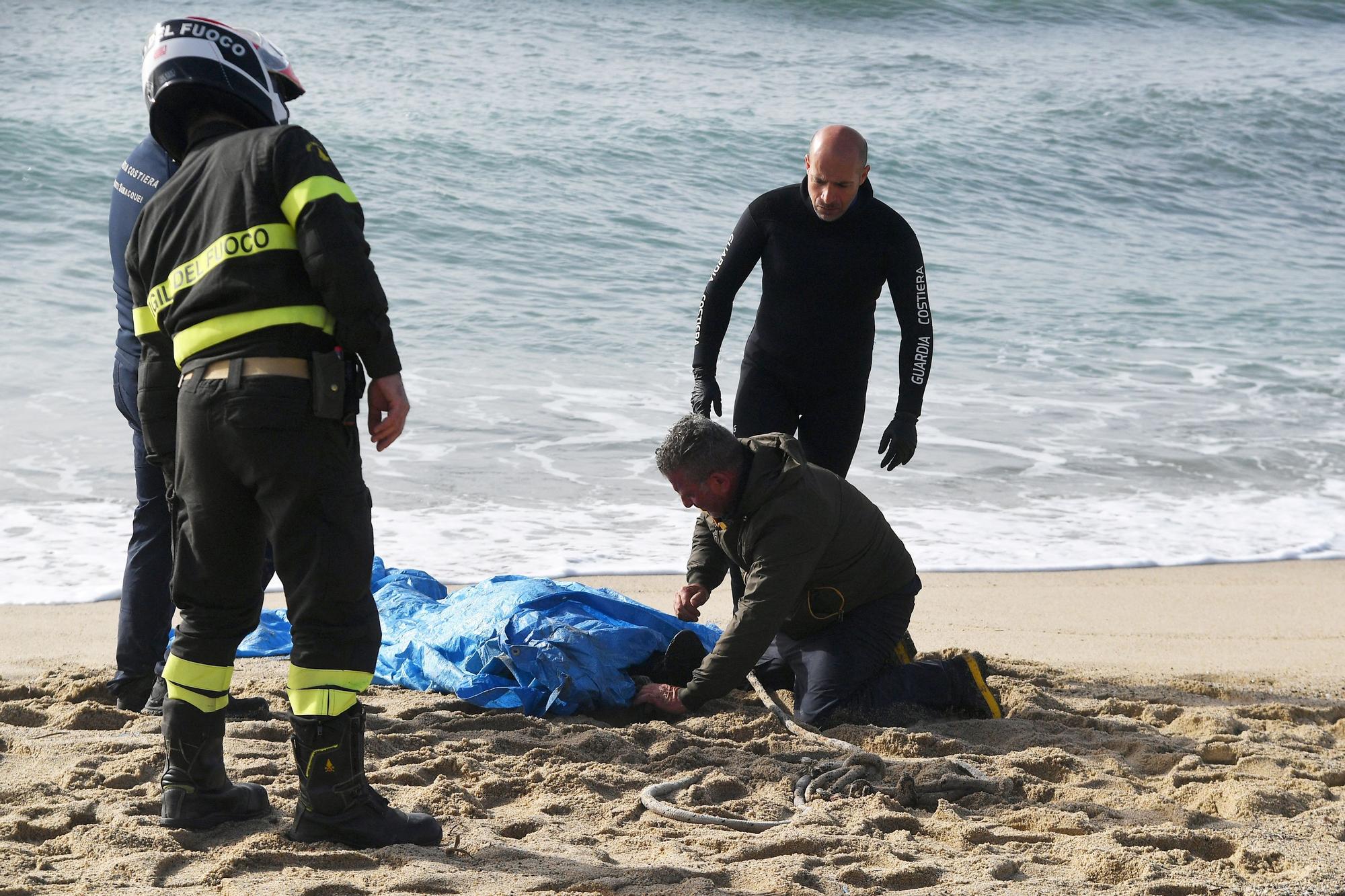 Miembros de los equipos de rescate cubren un cuerpo en la playa, dos días después de que un barco de migrantes naufragase en Steccato di Cutro, en la región italiana de Calabria, el 28 de febrero de 2023, dejando al menos 64 muertos