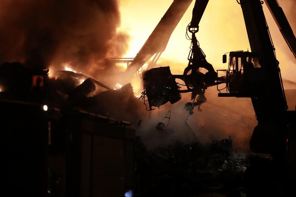 Labores de extinción del incendio de un desguace en Gijón